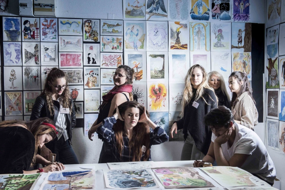 Étudiants posant devant un mur d'illustrations aquarelle au campus ESDAC Strasbourg