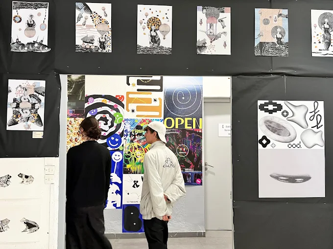 Étudiants observant des affiches et illustrations graphiques exposées au campus ESDAC Strasbourg